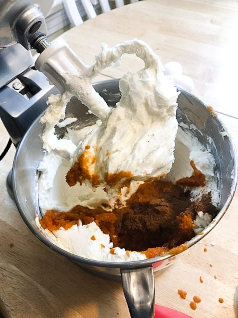 spices being added to a bowl of batter with a mixer