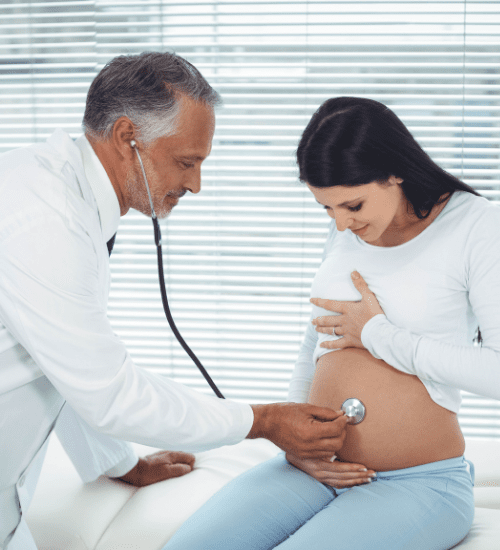 doctor listening to a pregnant woman's' belly with a stethoscope