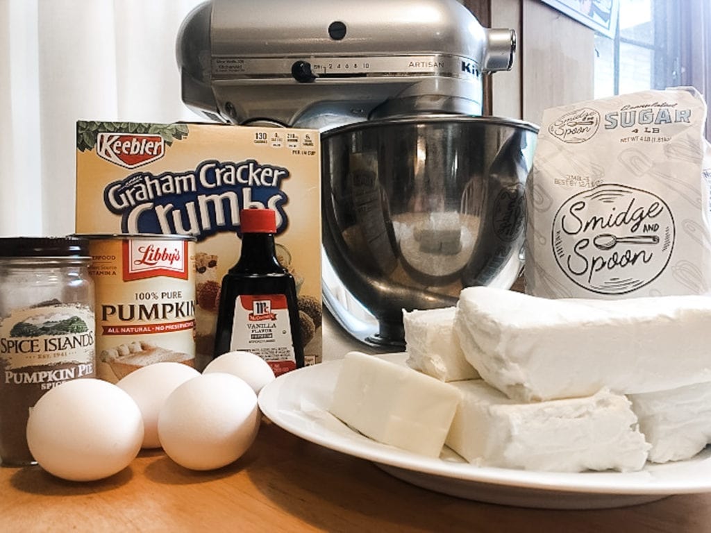 eggs, cream cheese, gram cracker crumbs, vanilla, pumpkin pie spice, and sugar in front of a mixer