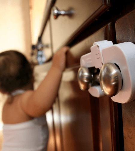 a small child holding a cabinet with child locks