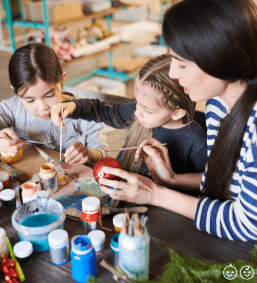 kids and mom painting Christmas ornaments at a table