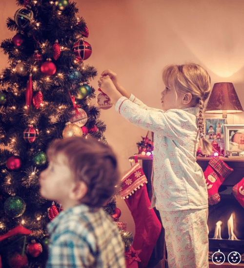 two young kids decorating a Christmas tree for the holiday season