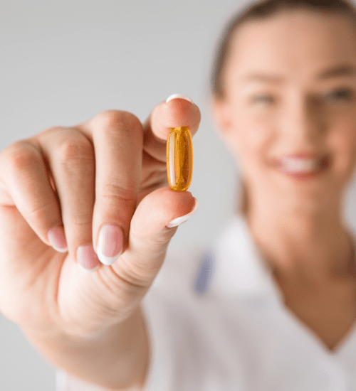 woman holding a vitamin with two fingers