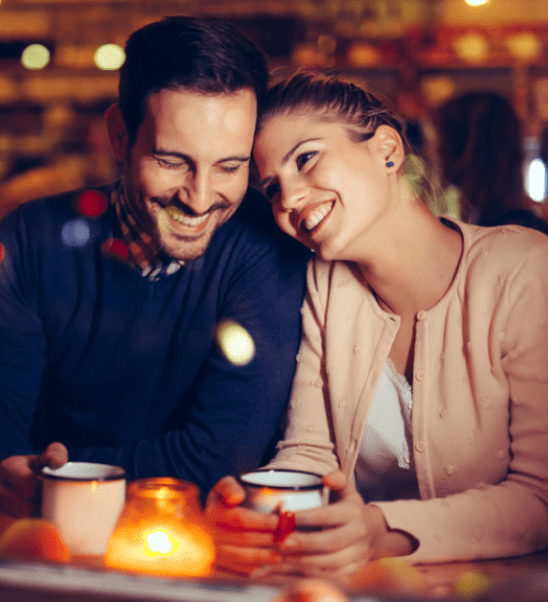 a new twin mom and man laughing while holding coffee, sitting next to each other