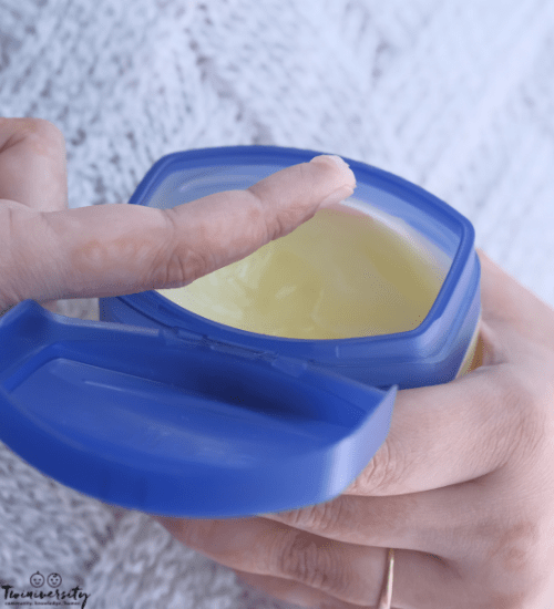 a woman holding petroleum jelly open to use for her baby skin care