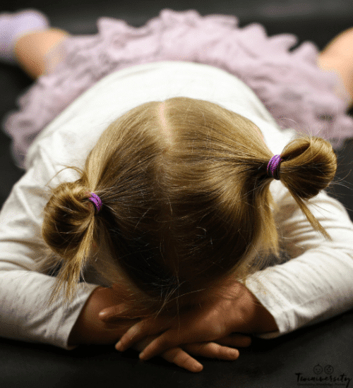 little girls laying on her belly on the floor with her head in her hands throwing a tantrum