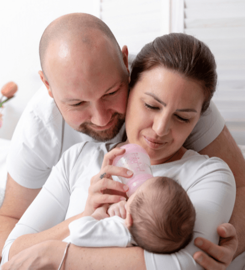 couple feeding newborn baby with bottle