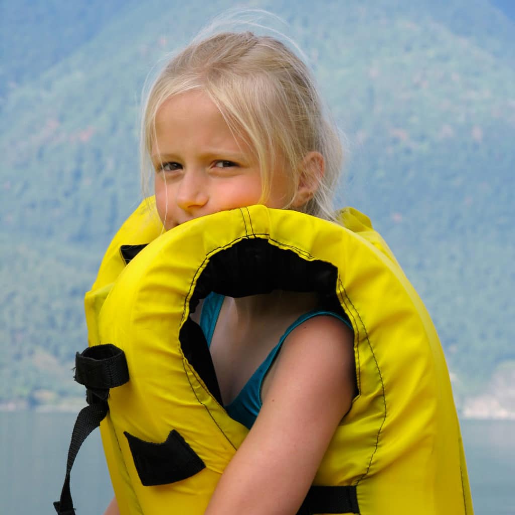 Young blonde girl in a yellow life jacket that is way too large for her.