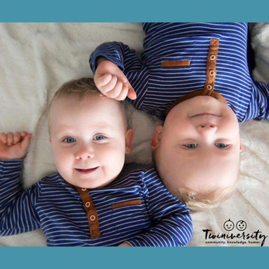 identical twin boys lying head to head and smiling at a camera