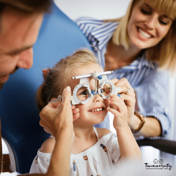 young child undergoing eye exam with parents looking on happily