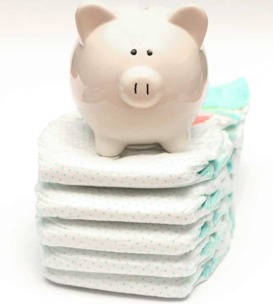 White ceramic piggy bank resting on top of five new, still folded diapers
