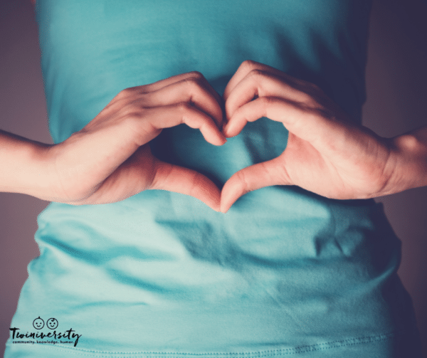 woman forming a heart with her hands over her stomach
