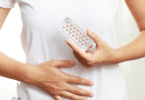 woman holds package of birth control pills in front of stomach