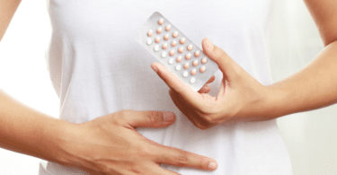 woman holds package of birth control pills in front of stomach