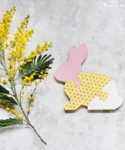easter bunny puzzle pieces put together and a green and yellow flower on a grey marbled background