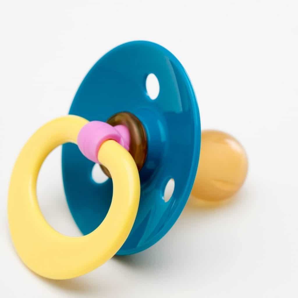 Closeup picture of a round pacifier with teal base and yellow handle