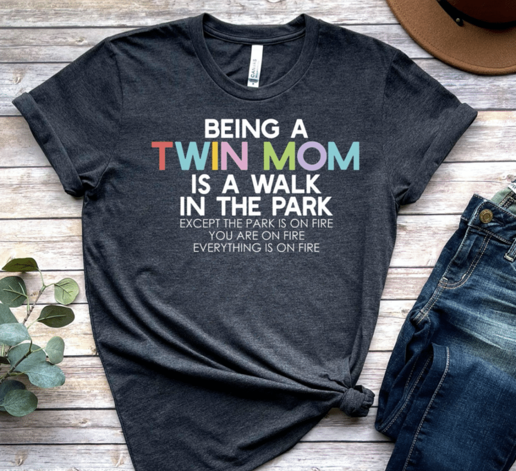 Dark gray tee shirt with white and multicolored text reading "Being a Twin Mom is a walk in the park except the park is on fire you are on fire everything is on fire"