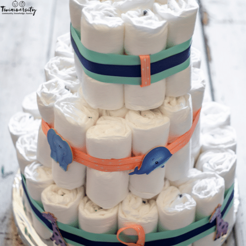 a 3-tiered white diaper cake with colorful ribbons and animals on the ribbon