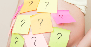 pregnant woman with question marks on post-it notes stuck to her abdomen