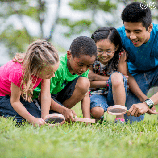 a group of young kids using magnifying glasses to look in grass