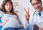 pregnant woman at doctor's appointment doctor holding up two fingers