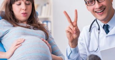 pregnant woman at doctor's appointment doctor holding up two fingers