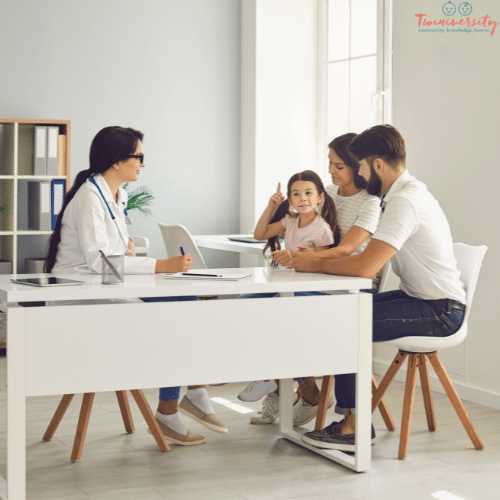 a doctor sitting at a desk talking to a couple with a young girl in their lap about early intervention