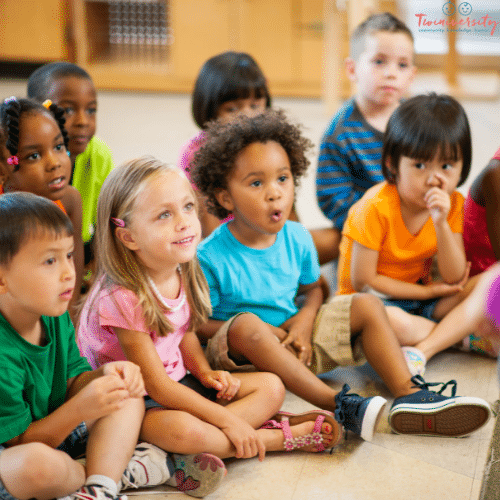 a small classroom of pre-school aged children sitting on a floor together