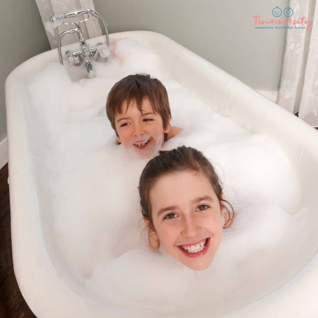 Young girl and boy siblings in a claw tub bubble bath together. There heads are the only thing showing because of the massive amounts of bubbles