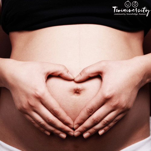 pregnant woman makes shape of a heart on her belly with her hands