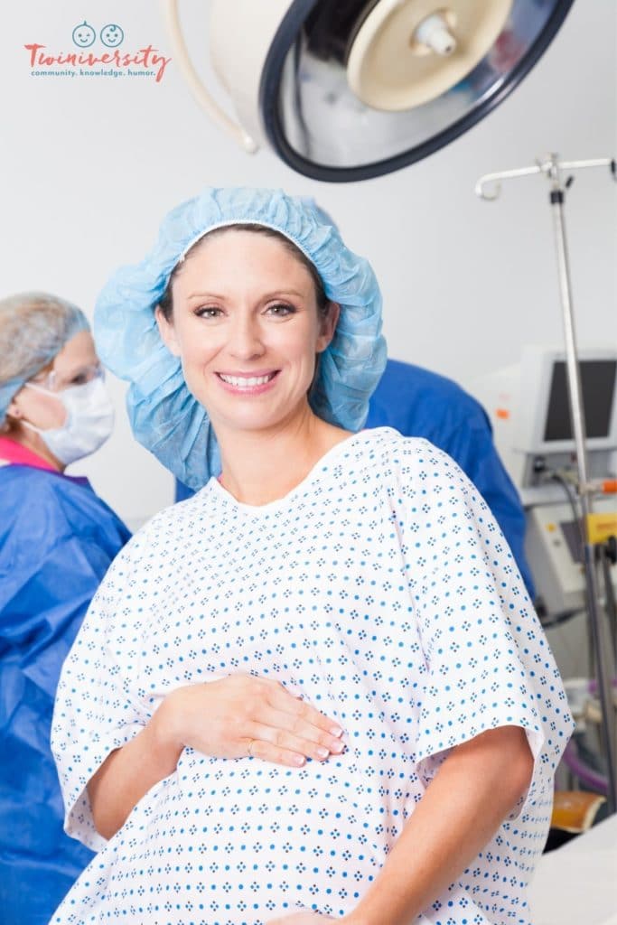 Pregnant woman in a hospital gown holding her pregnant belly in the operating room before her c-section
