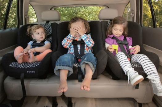 Three kids ranging in ages 3, 2 & 1 years old are sitting in Cosco Scenera Next car seats in the back seat of a sedan.