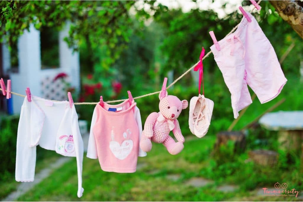 Pink shorts, ballet shoes, bear, shirt and sweater are hanging from twine as bunting