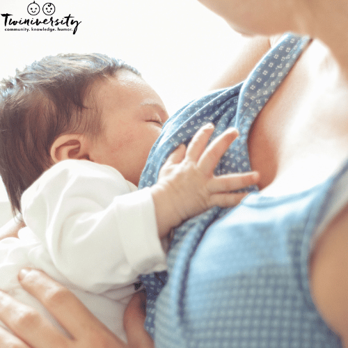 a woman nurses a baby in an upright position with no milk coming out of baby's nose