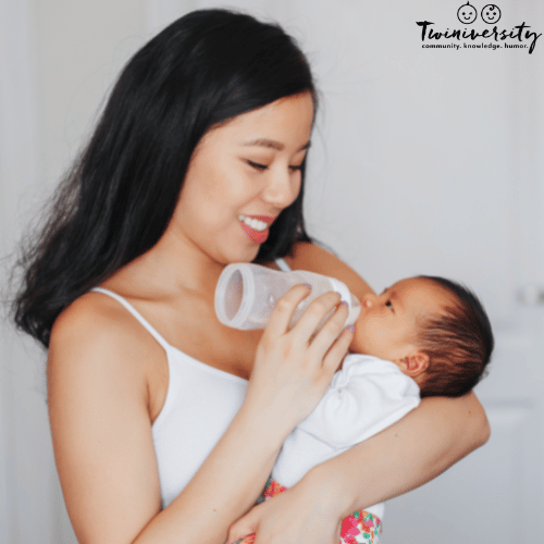 a woman holds a baby while bottle feeding them upright to prevent milk coming out of baby's nose