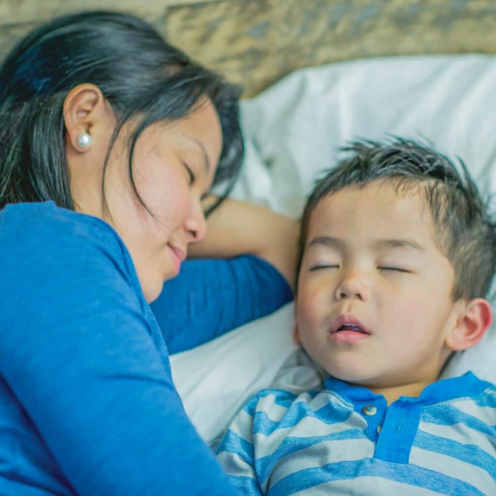 Mom laying with son until he falls asleep to make sure he does not get out of his bed.
