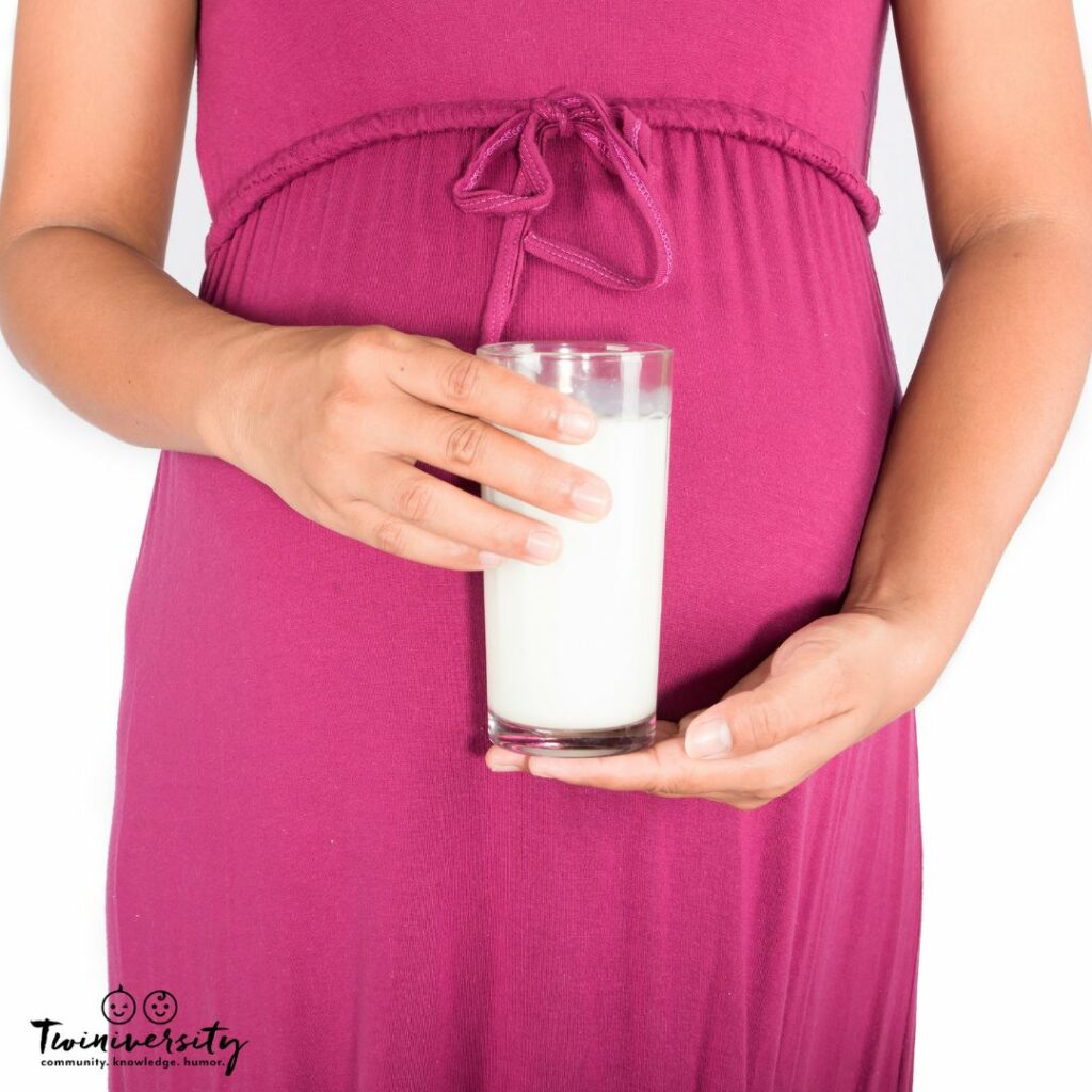 Pregnant lady holding a glass of milk in front of her belly 