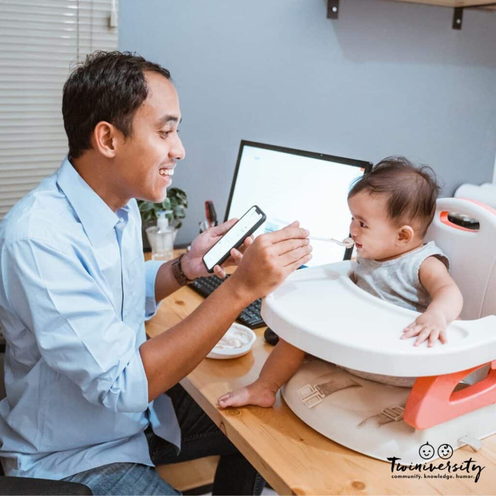 A dad working from home while feeding one of his kids