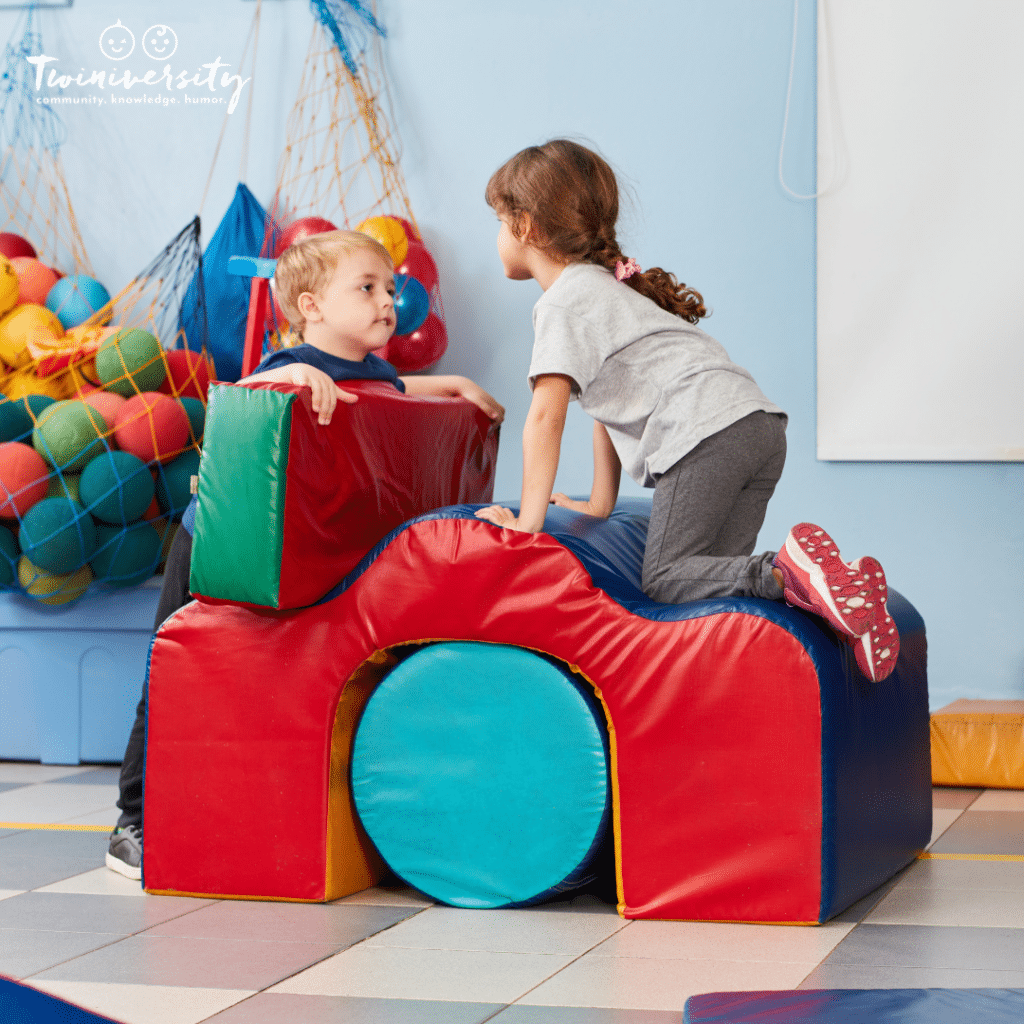 2 kids climbing at a kid's gym working on their gross motor skills