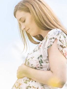 maternity baby shower dress. A woman cradling her baby bump