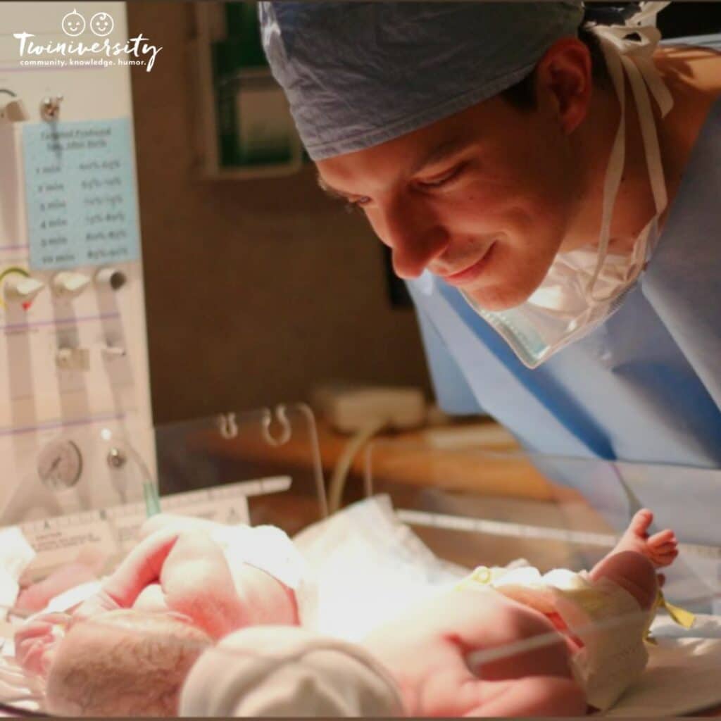 newborn twins being cared for by a happy doctor