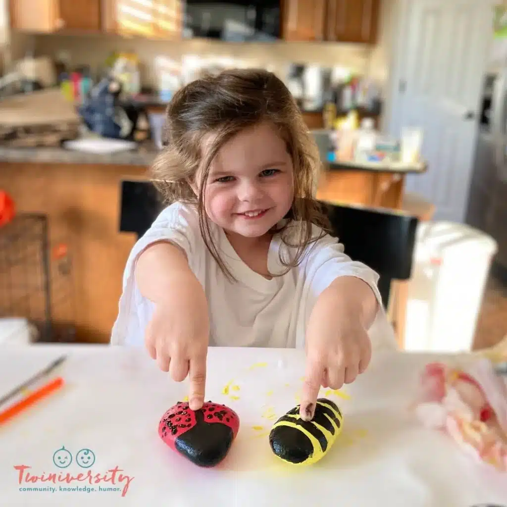 Little girl showing off her summer art project of painting rocks.