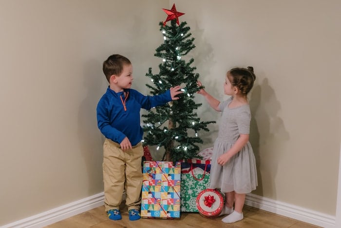 twin toddlers standing next to small christmas tree the 4 gift rule