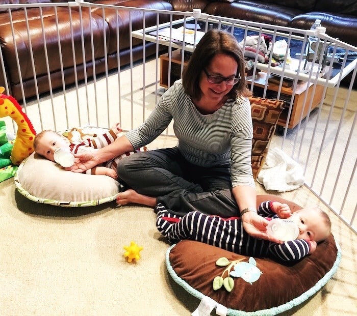 grandma feeding infant twins on the floor