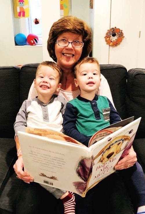 grandma holding twin boys in her lap while reading a book