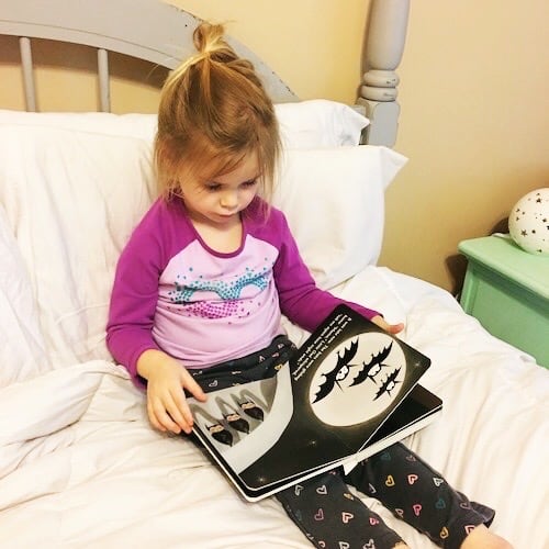 little girl reading a book in bed kids to read