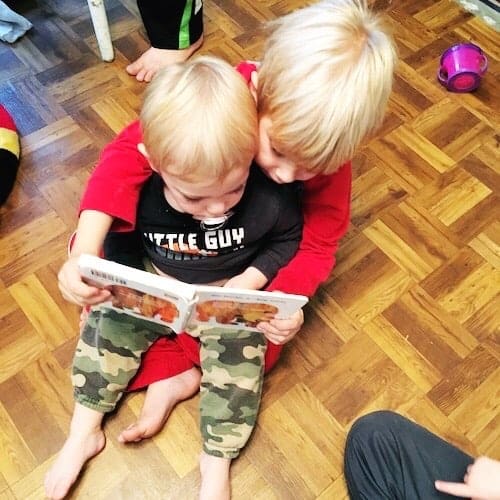 twin toddler boys sitting in each others laps reading a book kids to read