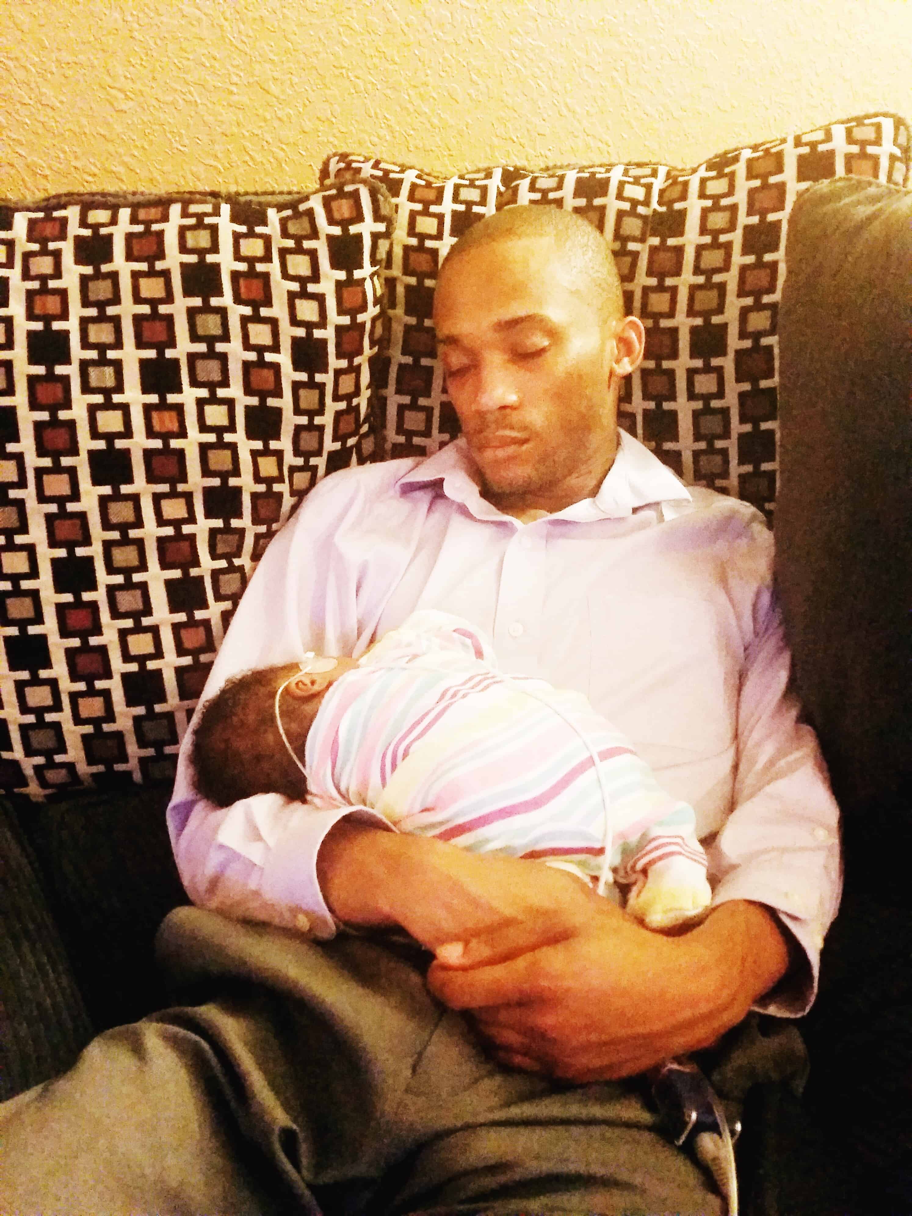 dad sleeping on couch and holding newborn baby gift for newborn twins