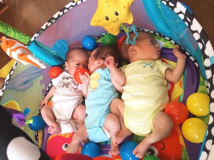 triplets babies on a play mat