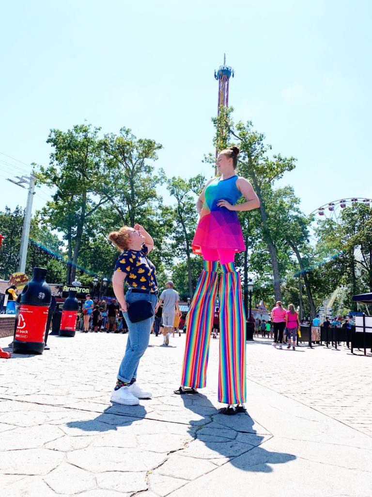 Girl standing by woman on stilts at Six Flags ticket prices